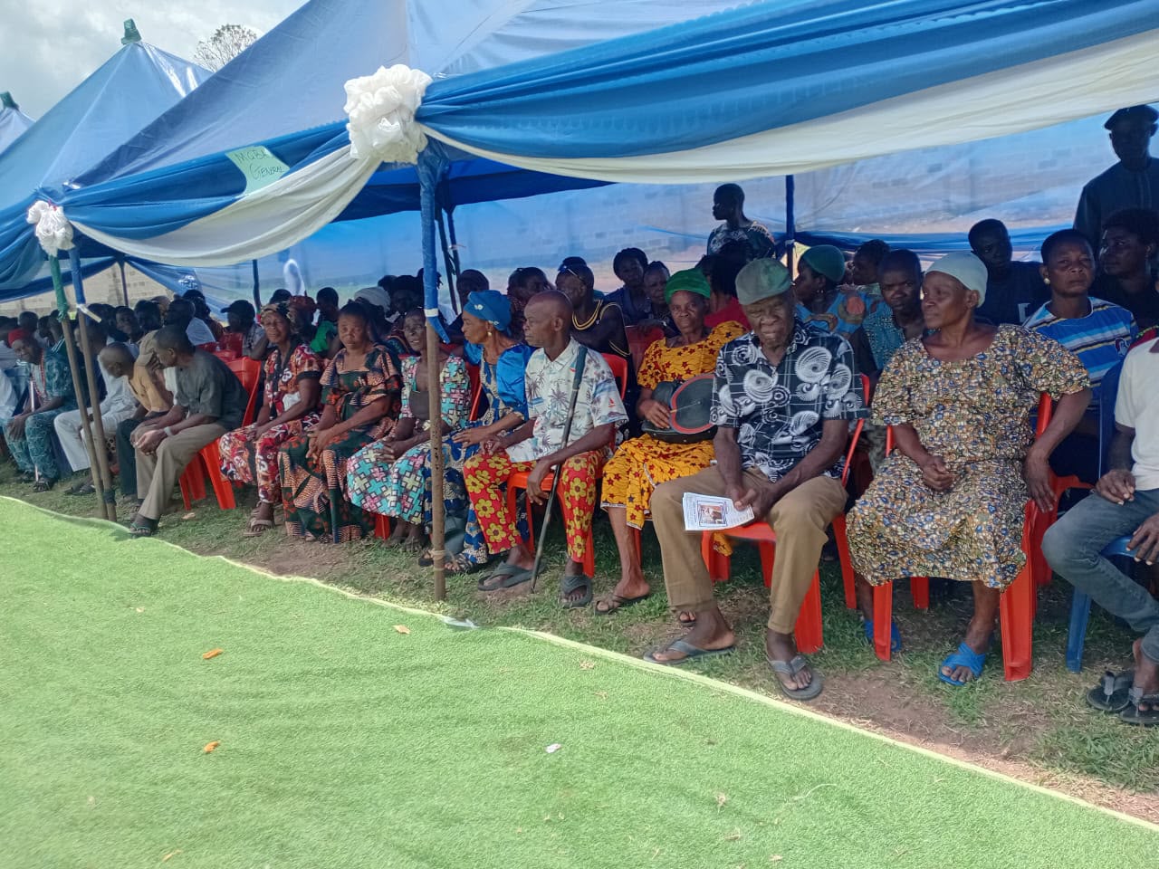 Community members seated under a canopy at a foundation outreach event